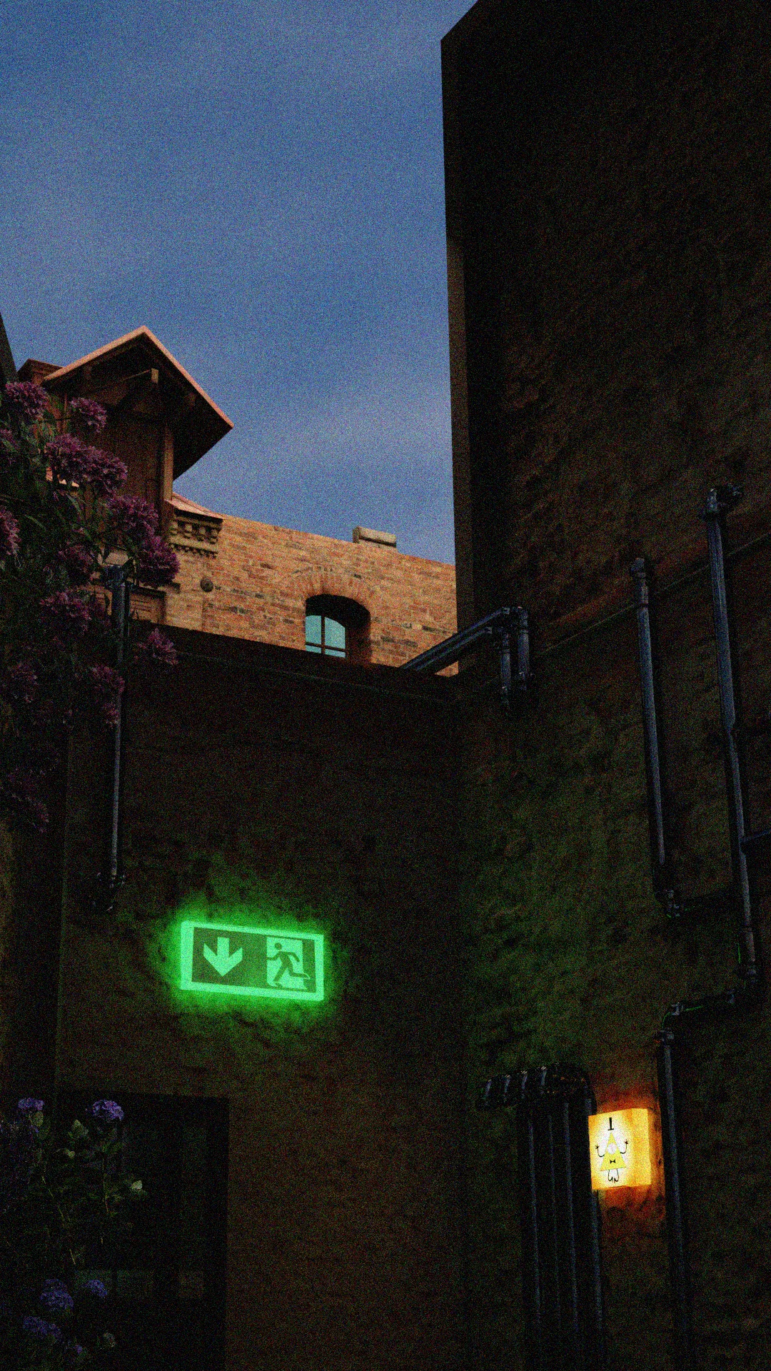 A narrow London street corner at dusk, with brick buildings and a glowing green exit sign