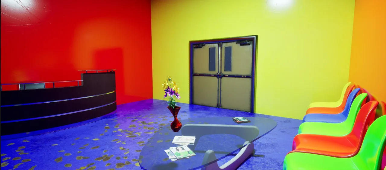 A reception counter, a glass table and a row of colourful chairs